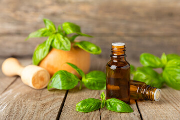 Basil essential oil on a textured wooden background. Basil essential oil and fresh leaves. Aromatherapy. Aroma oil. Medical herbs. Alternative medicine. Place for text. Copy space.