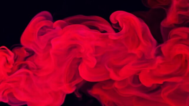 Red smoke billows and twists against a dark background, creating dynamic shapes that evoke mystery and energy.