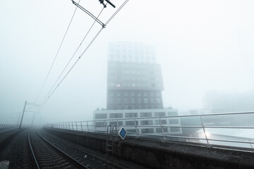 Fototapeta premium Foggy morning at Sloterdijk Station: cyclists and commuters navigate through the hustle of a workday, enveloped in mist, capturing the essence of urban life and daily routines in Amsterdam.