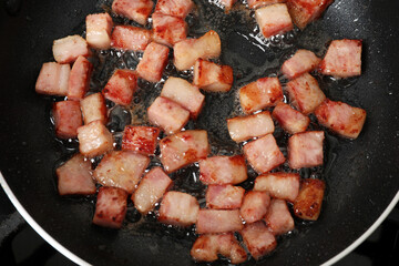 Pieces of bacon frying in pan, top view