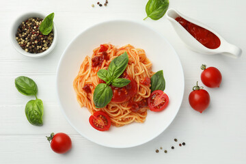 Delicious pasta with tomato sauce, peppercorns, vegetables and basil on white wooden table, flat lay