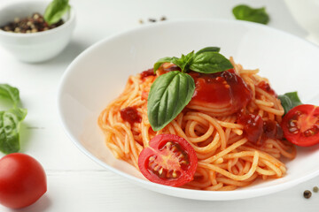 Delicious pasta with tomato sauce, peppercorns, vegetables and basil on white wooden table, closeup