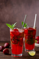 Fresh strawberry mojito lemonade with ice and mint in glass on brown wooden table. Cold summer drink. Sugar free, nonalcoholic. Vertical orientation.