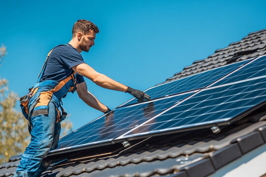 man with installing soler panels on roof