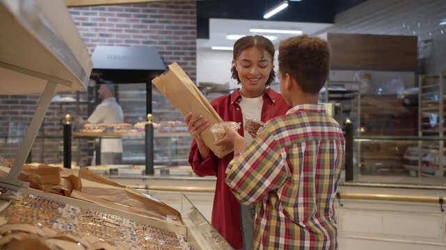 Attentive woman picking baguette and smiling to preteen son
