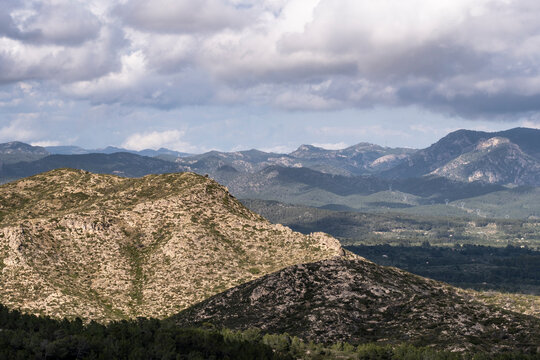 A breathtaking view of a rugged mountainous landscape, with distant rolling hills under a partly cloudy sky, showcasing nature's grandeur and the beauty of Earth in Tarragona Spain
