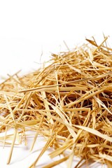 A pile of straw sits on top of a white surface, ideal for use in rustic or farm-themed designs