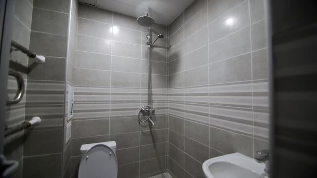 Shower unit toilet bowl and sink in empty illuminated bathroom. Minimalist washroom with modern utilities in hotel. Interior design
