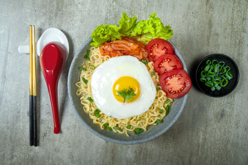 A bowl of instant noodles with eggs and tomatoes