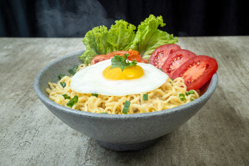 A bowl of instant noodles with eggs, tomatoes, and lettuce
