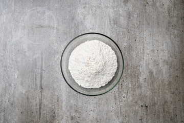 A bowl of white flour sits on a grey countertop