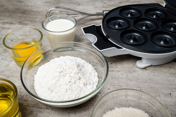 A table with several bowls of ingredients, including flour, sugar, and oil