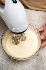 A person is making a cake and has a bowl of flour and sugar on the table