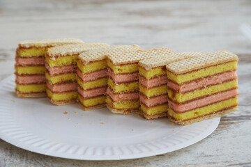 Sliced sponge cake on a white disposable plate on a table closeup, fruit sponge, rustic home baking,