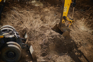 Excavator scooping earth with a bucket in a close-up shot, performing earthworks at the initial...