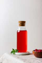 Raspberry drink in the glass bottle on the light background.