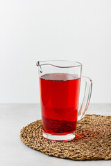 Red color drink in the glass jug on gray background.