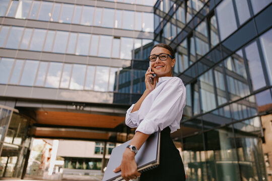 Confident and successful businesswoman confidently stands outside a modern office building