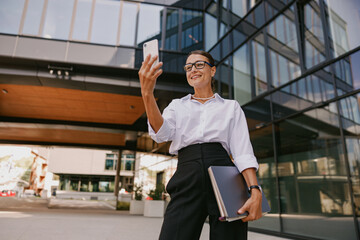 A Confident Businesswoman Engaging with Her Smartphone While Outdoors in the City