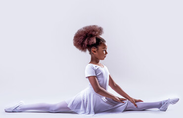 Ballerina in a white leotard. Little ballerina girl laying on the ground. Flexible little african...
