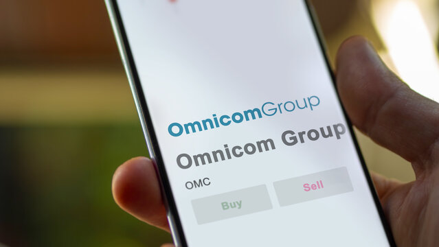 Omnicom Group on the screen of an exchange. Omnicom Group price stocks, $OMC on a device,New York City, New York. Close up on logo.