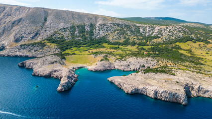 An aerial view of Reef Mala Glavina on Krk Island, Croatia, captured by a drone. This stunning image showcases the rocky reef surrounded by the clear blue waters of the Adriatic Sea