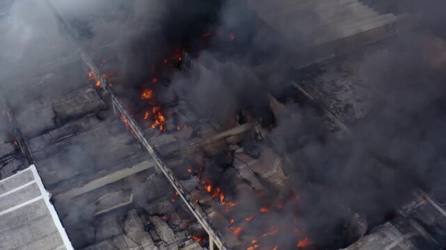 Aerial shot of the collapsed building in Gaza following Israeli missile attacks. Shows flames, smoke, and a hostile environment with devastation, ruins, and structural collapse in a conflict zone.