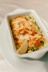 delicious casserole with fresh vegetables and aromatic herbs on a beautiful white plate in a cozy and nice restaurant