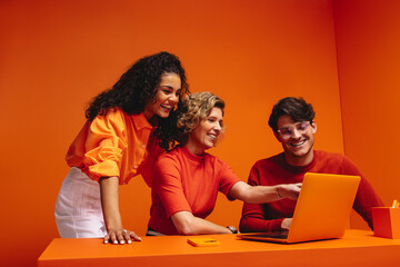Creative business team collaboration in a vibrant monochromatic office setting with bold orange colors