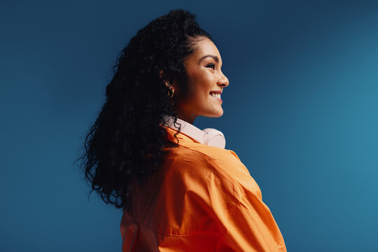 Smiling woman with headphones in side profile, vibrant color blocking and colorful setting