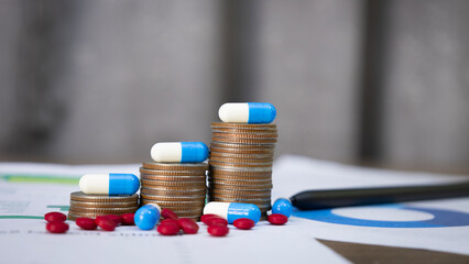 Blue and white capsules on a pile of coins and pills, meaning health insurance, medical expenses and pharmaceutical, finance, saving money, business, financial and medical healthcare concept.