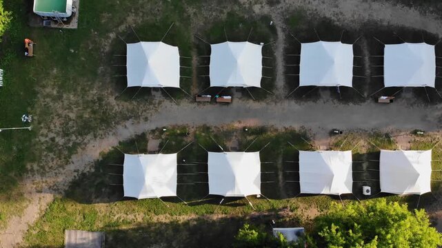 Top view of several large white tents standing in a row at the campsite.