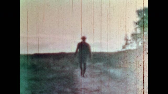 Archive film, Scary man walking swinging axe in countryside nature. Dangerous maniac, criminal butcher. Halloween fear concept. Evil killer on deserted empty road meeting victim. Vintage retro 1960s