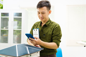 Asian businessman works alone at his desk, surrounded by a laptop, paperwork, tablet, and calculator, focusing on home and land mortgage agreements in a modern house model.