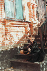 Girl sitting on the stairs with pumpkin. Celebrating Halloween