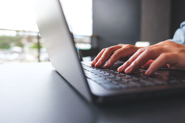 Closeup image of a woman hands working and typing on laptop computer keyboard