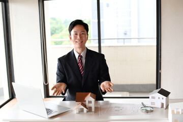住宅模型の前で提案するスーツ姿の男性