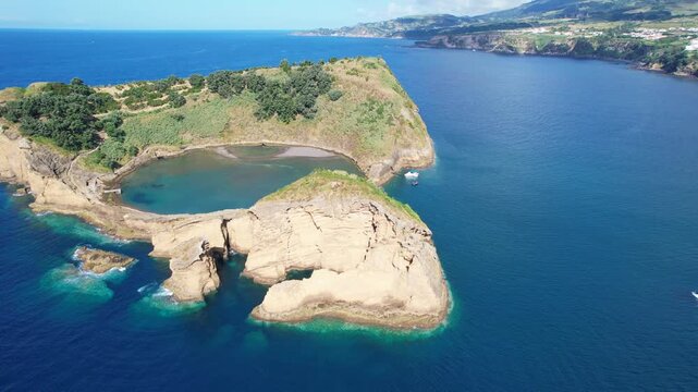 Aerial view of Ilheu de Vila Franco do Campo on a bright summer day, showcasing its turquoise lagoon and volcanic beauty off Sao Miguel, Azores, Portugal
