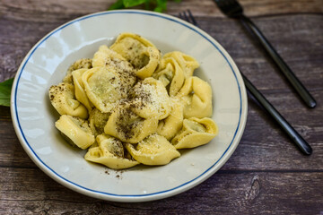 Home made vegetarian  italian   Tortellini with pesto genovese filled with   spinach   and parmesan cheese, decorated with fresh basil