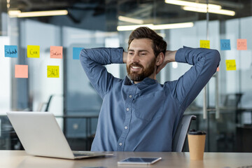 Relaxed businessman taking break at office desk with laptop and phone