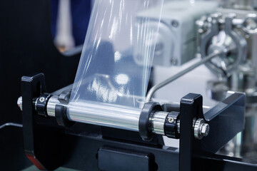 roll of plastic packaging film on the automatic packing machine in food product factory. industrial and technology concept.
