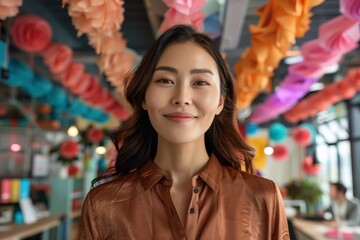 Obraz premium A cheerful woman standing in a beautifully decorated festive setting with colorful paper decorations in the background, smiling warmly and enjoying the joyful atmosphere.