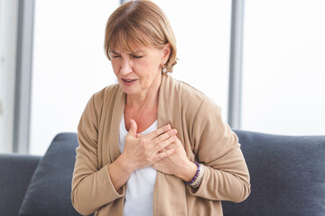 Woman with pain on heart, Mature female presses hand to chest has heart attack suffers from...