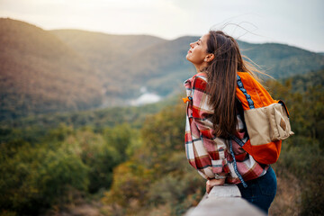 Young woman breathing pure air in a forest. Young woman hiking and going camping in nature. Person...