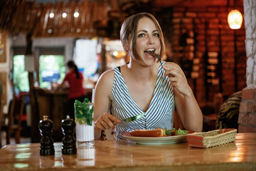 Front view. Woman is in the restaurant with food and drink