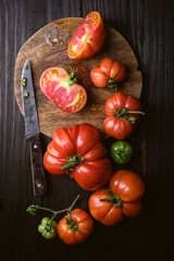 Top view on ripe red tomatoes with round cutting board, old knife and rustic wooden table. Food photography