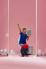 Happy and excited child, young boy sitting in toilet and emotionally watching online soccer game...