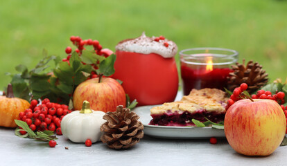 Autumn still life with a cup of hot coffee, blueberry pie, candle, pumpkins and rowan berries. Sweet homemade seasonal pie on a table. 