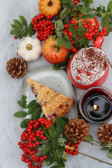 Autumn still life with a cup of hot coffee, blueberry pie, candle, pumpkins and rowan berries. Sweet homemade seasonal pie on a table. 