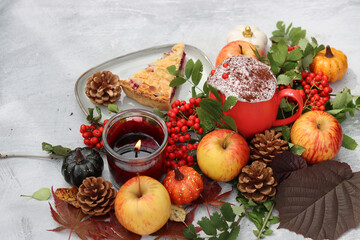 Piece of blueberry pie on a plate with autumn decorations, candle and red flowers. Light grey background with copy space. Cozy autumn food. 